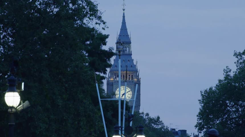 Upward view of a tower with a clock and lampposts in a late afternoon