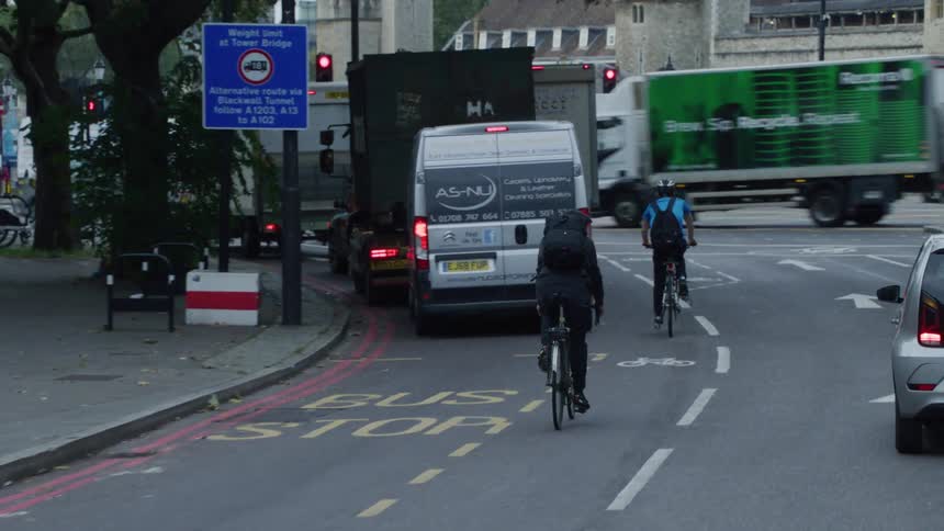 View of a busy street with private vehicles public transportation and cyclists