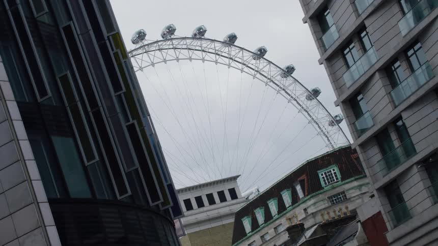 A ferris wheel sits near city buildings and a tunnel