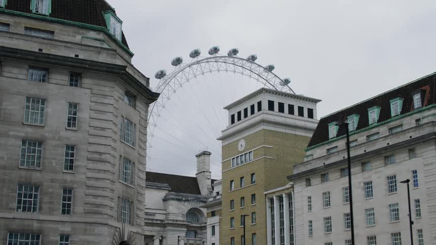 A ferris wheel behind buildings in a neighborhood during a cloudy day