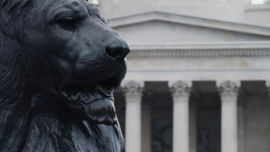 A bird flies past the statue of a lion