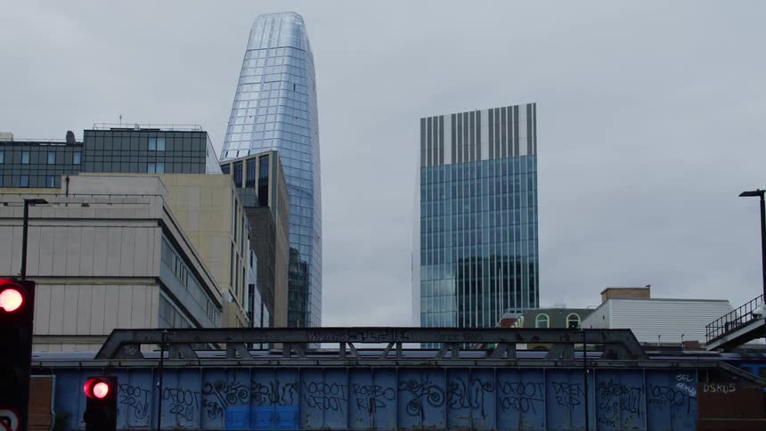 A train moves down rails in front of skyscrapers