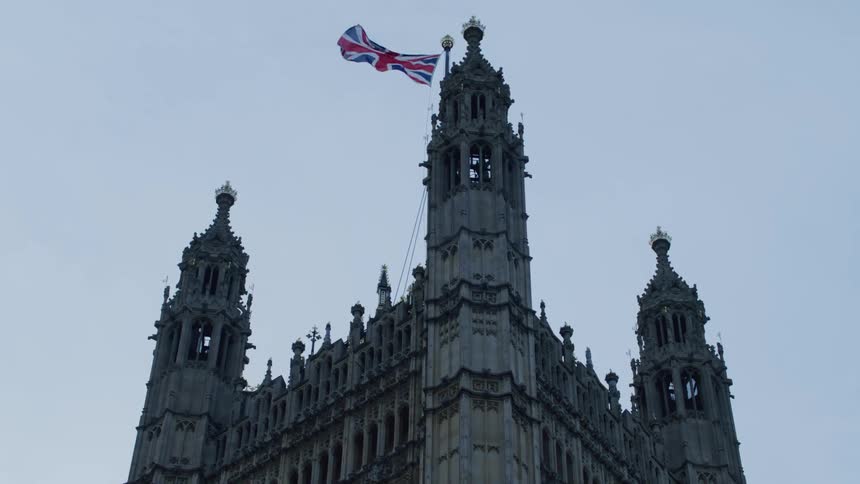 The top of a detailed gothicstyle building with a british flag flying atop