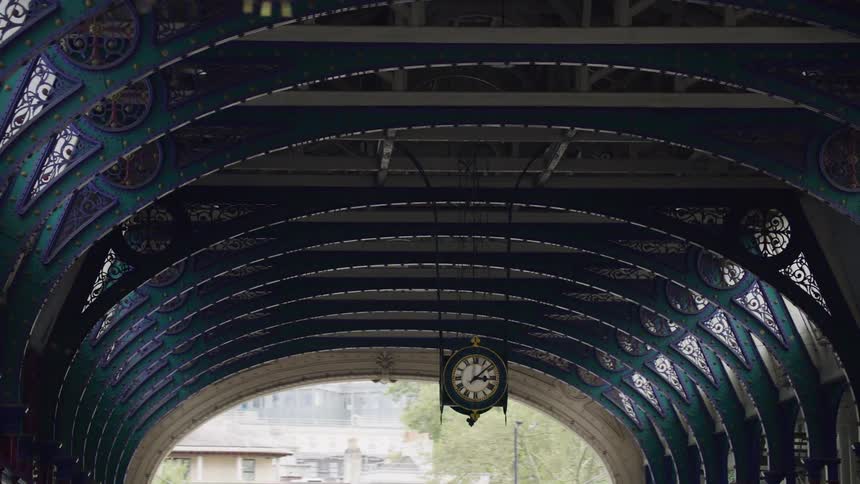 A clock hangs from the roof of a tunnel in a city
