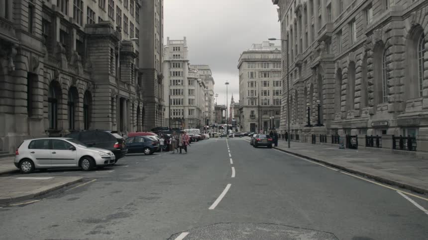 Pedestrians cross a city street between two buildings