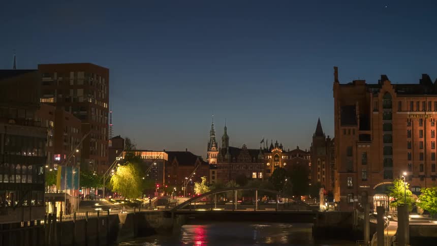 View of a city with buildings and a bridge over a lake at night