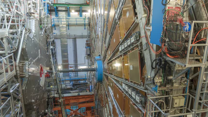 Several employees work on the construction of a large collider