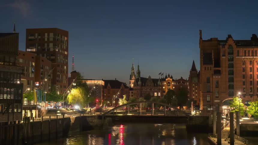 Panorama of a city at night with a small bridge over the river in timelapse