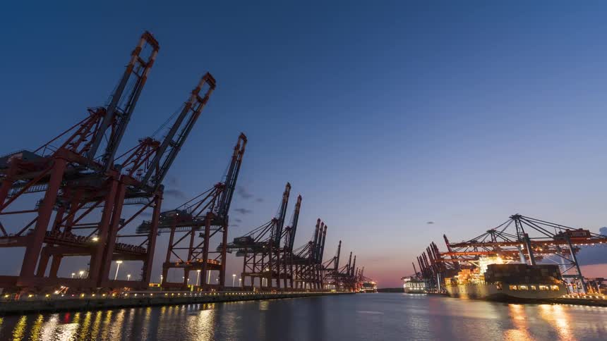 Loading crane loads container ship floating on reflective water at night