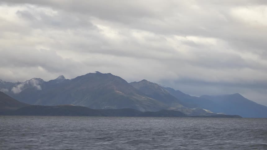Panorama of a mountain range by the sea on a cloudy day with clouds passing in timelapse
