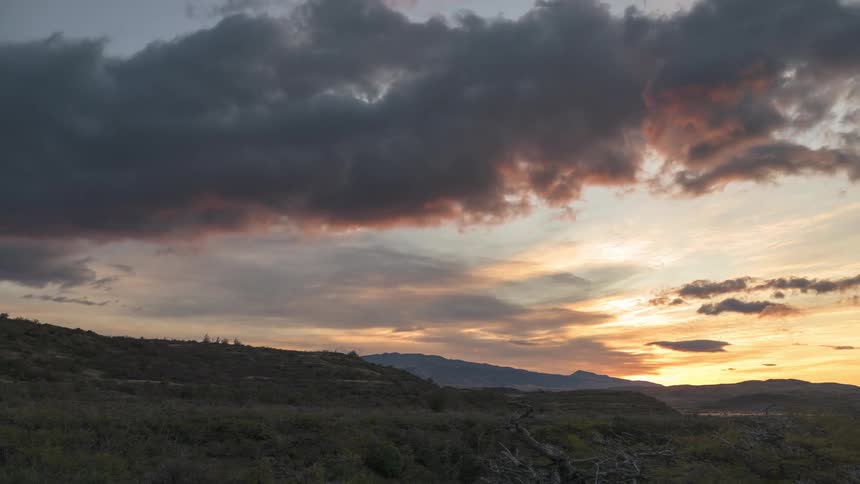 Red fades from clouds as sun sets over misty mountains