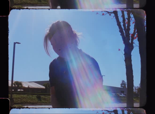 Woman gesturing with her arms and dancing in an outdoor setting with sunlight reflection