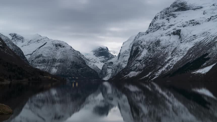 Clouds move over a body of water surrounded by mountains
