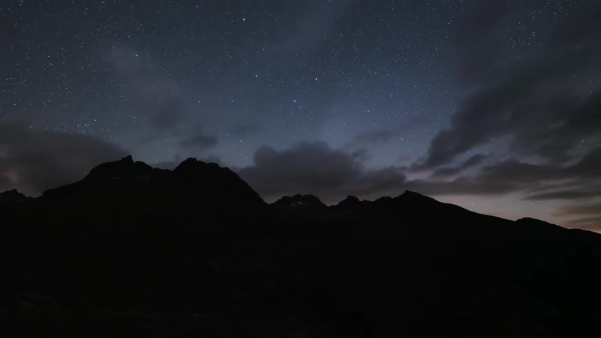 Comet Neowise with the silhouette of a mountain as the day darkens and clouds passing by
