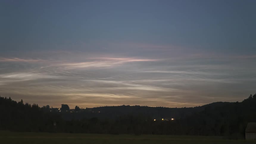 View of a field surrounded by trees with as display of Noctilucent Clouds (NLC's)