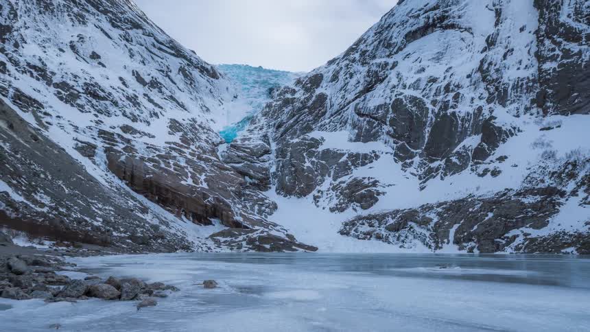 A frozen lake surrounded by snowcapped mountains during the day