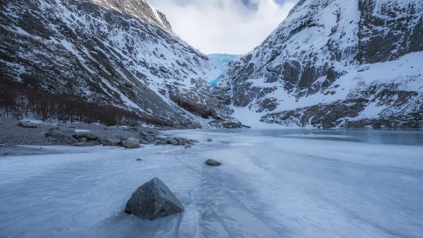 Panorama of a frozen lake with mountain ranges around it in timelapse