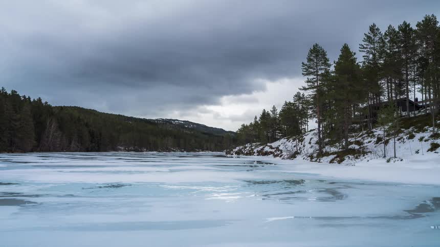 A frozen mountain lake in the forest on a cloudy winter day