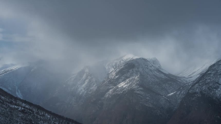 Snowcovered mountain range on a cloudy and foggy day