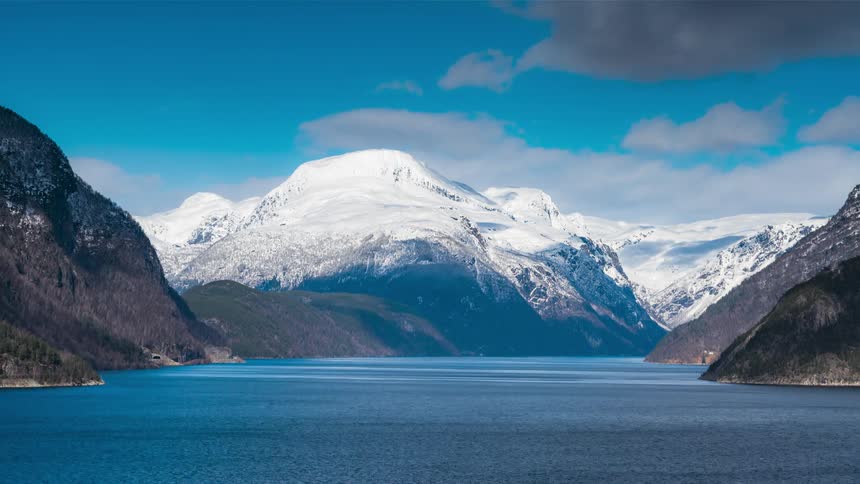 Waves move across a fjord surrounded by mountains