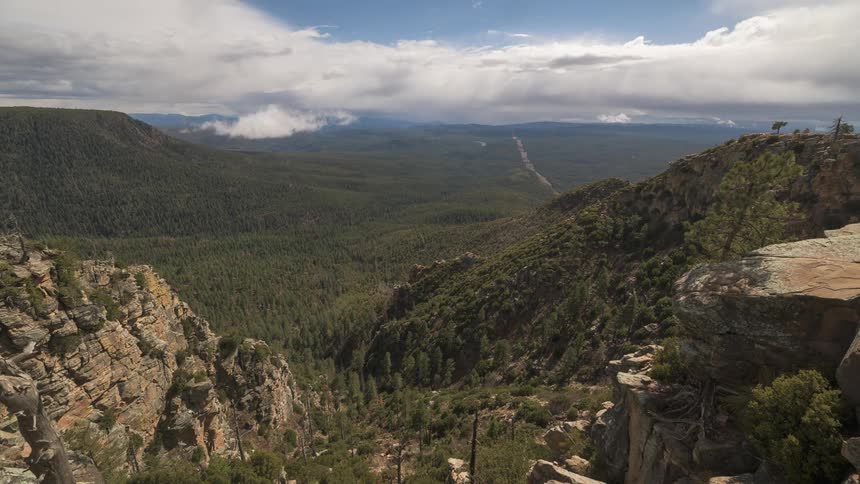 Panoramic view of a forested valley and some rocky mountain peaks on a cloudy summer day