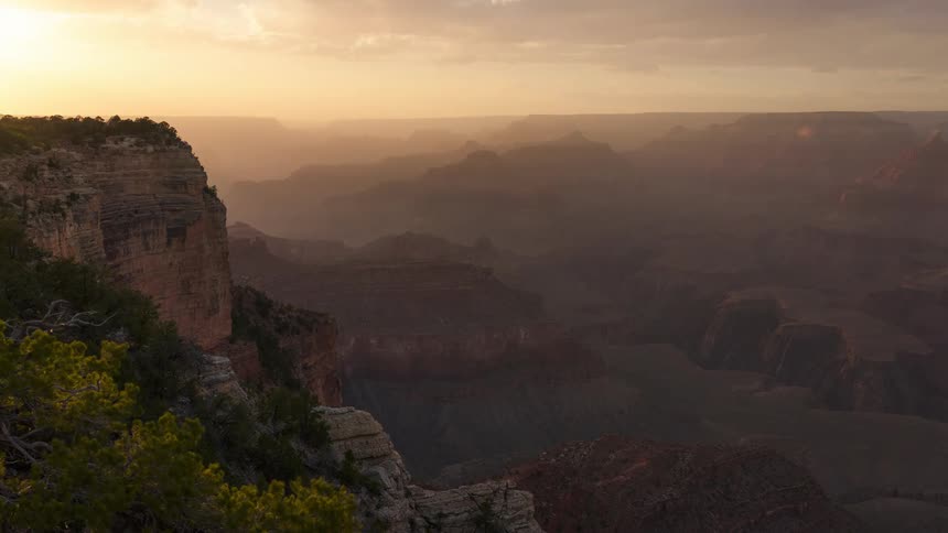 A scenic view of the grand canyon at sunset with intricate layers of rock formations bathed in soft golden light