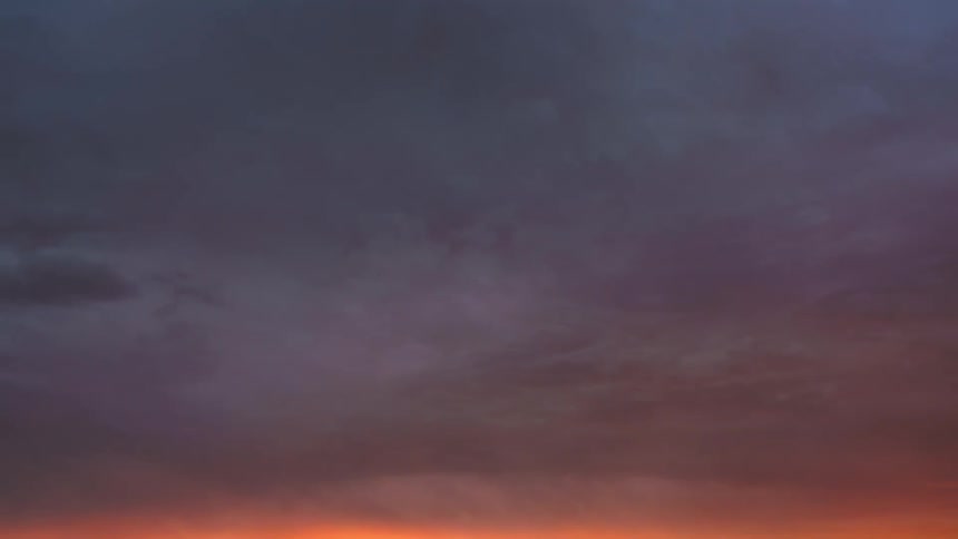 Landscape of the reddish and darkening sky in timelapse on a day with many clouds
