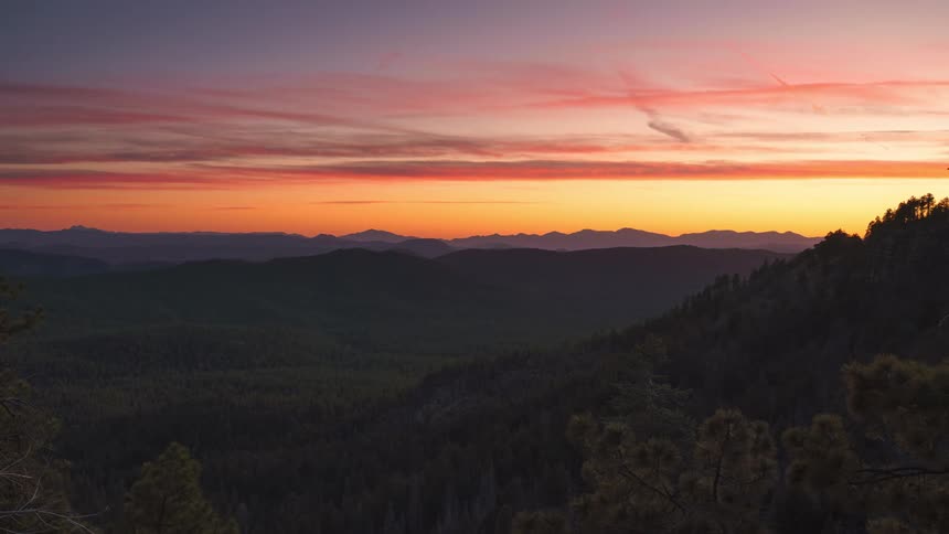 Panorama of mountain ranges rich in vegetation in an orange dawn sky