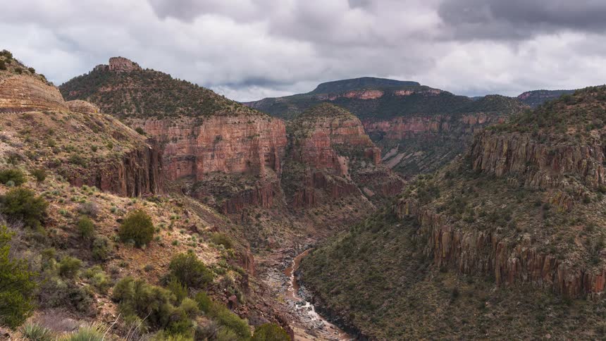 Panorama of valleys and canyons with a dry river in the middle and a cloudy day in timelapse