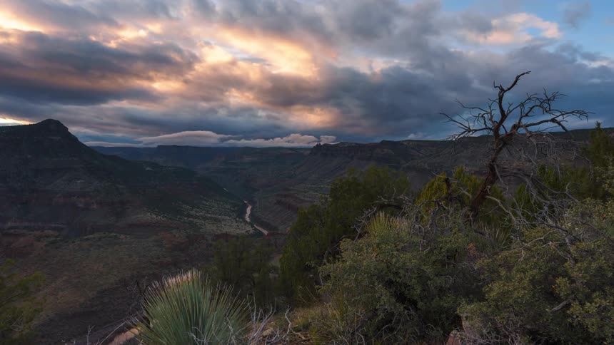 A rugged landscape during sunset with mountains and a winding river