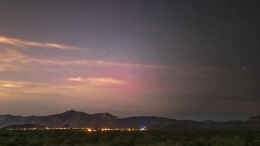 Panorama of a forest with city lights in the background in a purple sky with nebula and stars in timelapse