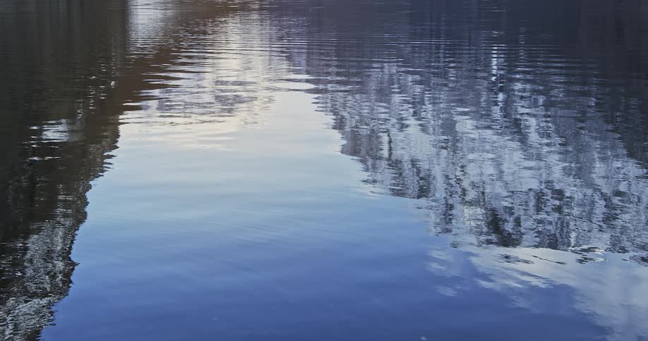 The image of two rocky snow covered peaks on the rippled surface of a lake
