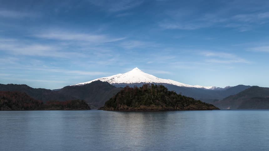 Clouds move over a mountain and an island in a lake