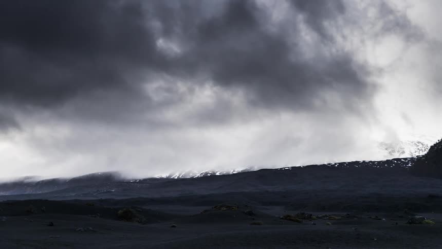 A snowy mountain in a desert landscape on a cloudy day