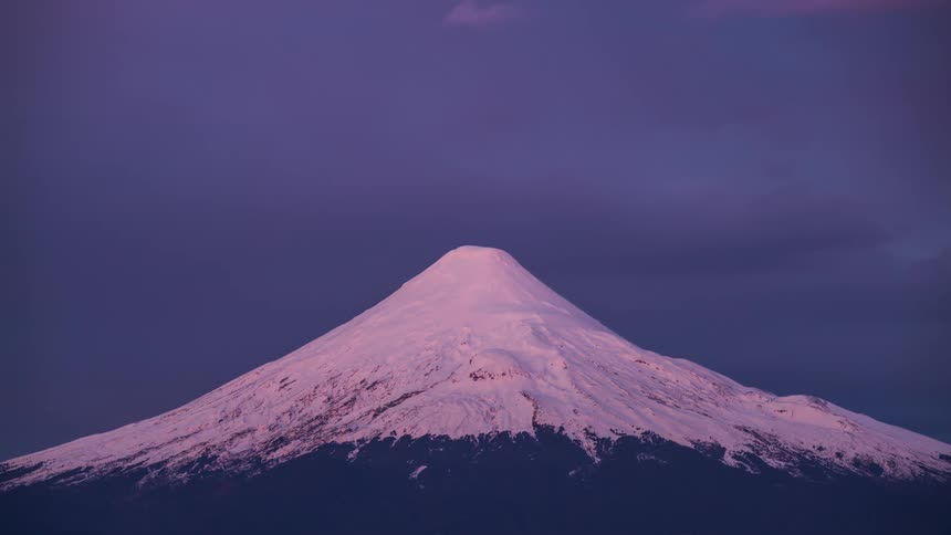 A colorful sunset of a symmetrical snow-capped mountain