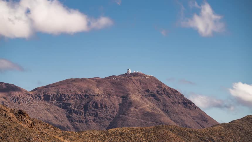 Panorama of an astronomical observatory on a rocky mountain with clouds passing by