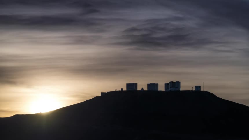 the sun setting behind the silhuettes of an astronomical observatory