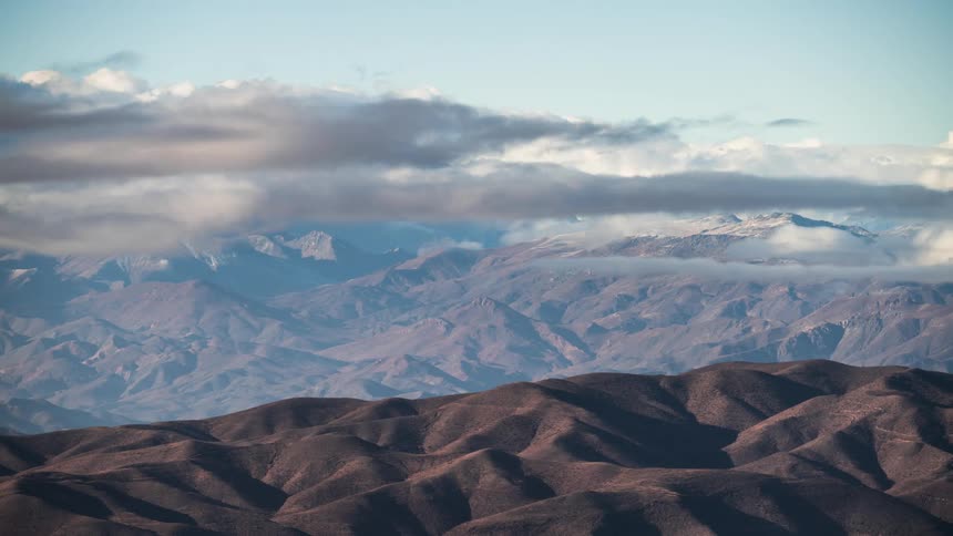 A mountain range partially covered by clouds in a clear sky