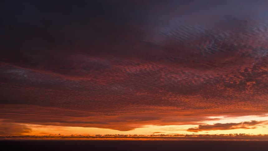 Clouds move through the sky at sunset over the ocean