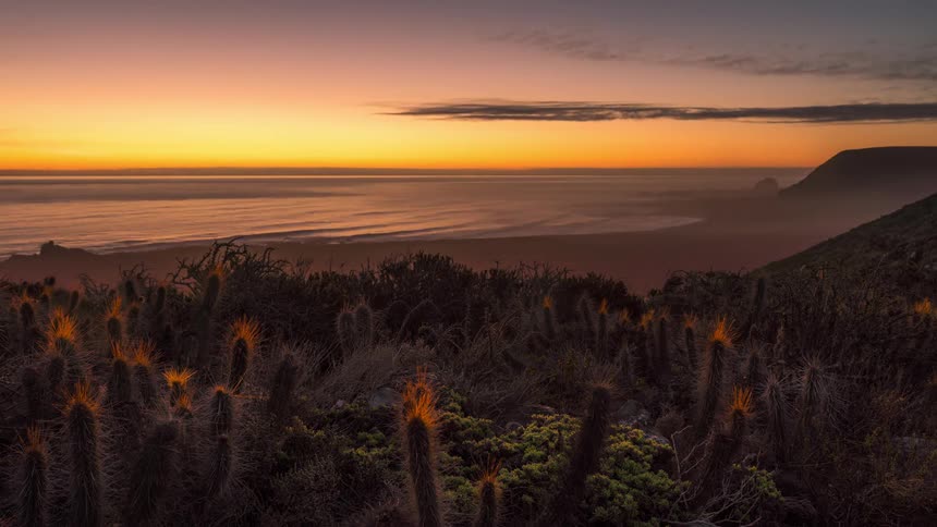 Landscape of a beach in timelapse of the sun setting and the day getting dark