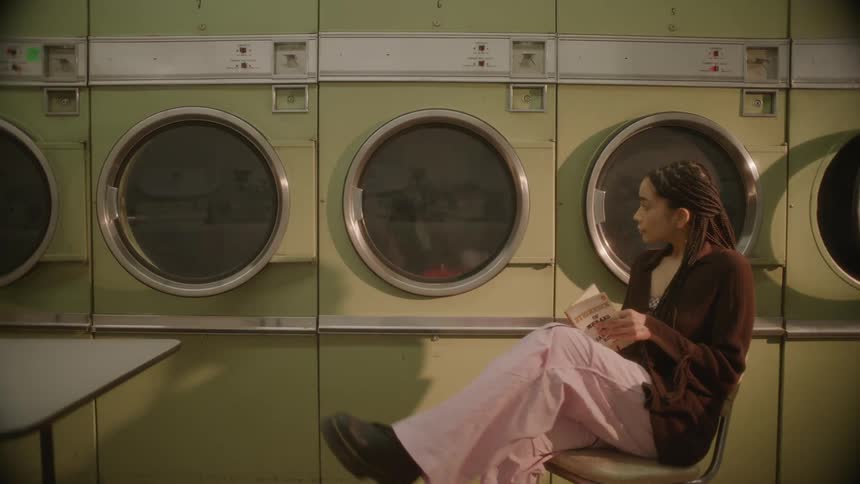 Woman sitting in a chair and reading a book next to washing machines