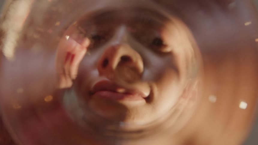POV as a young woman looks into a fish bowl and feeds the fish