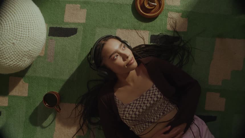 A woman is laying on the floor listening to music