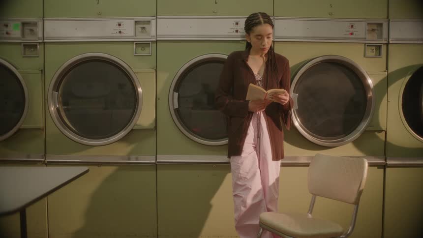 Woman in a laundromat reading a book