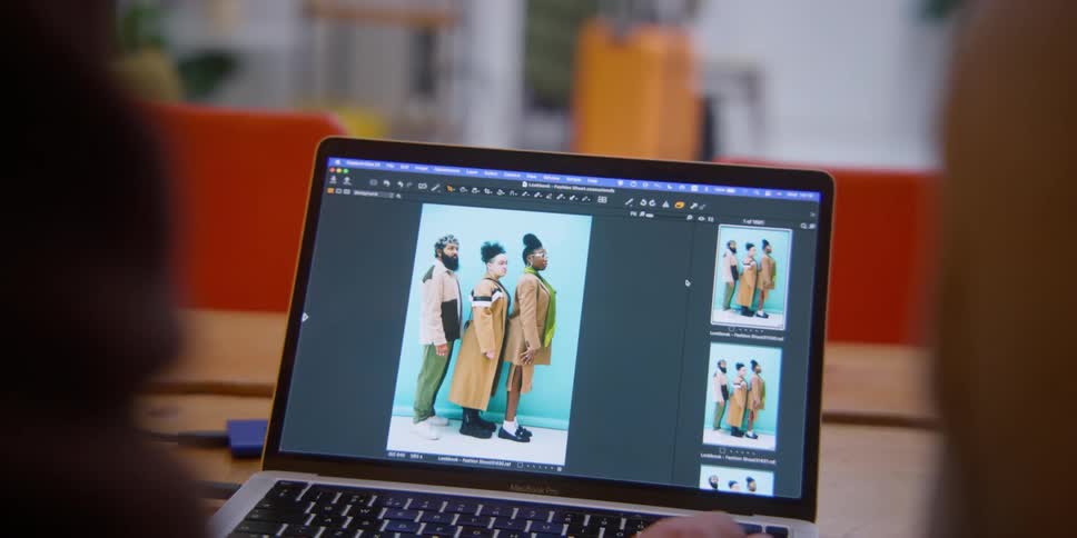 Two people fiddle with photos on a laptop
