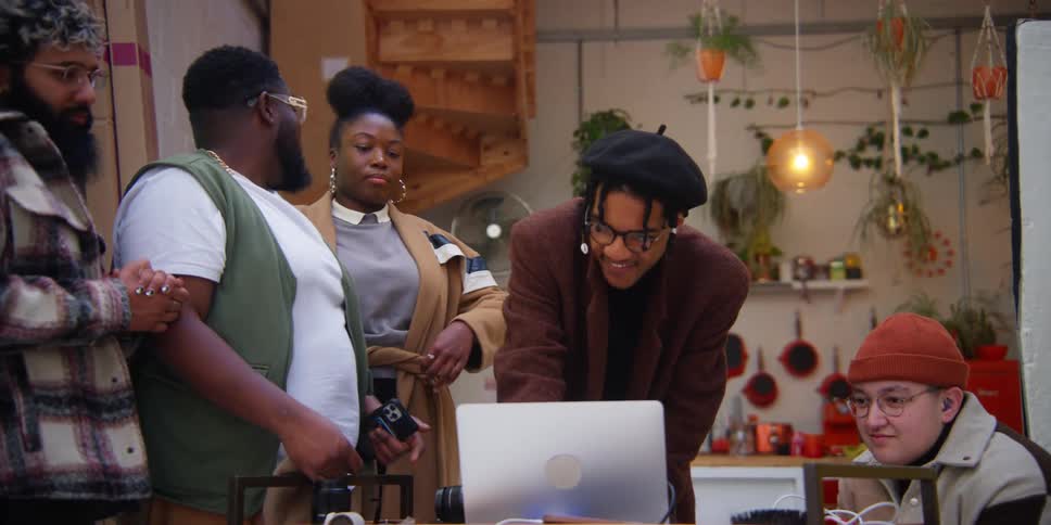 Small group of friends in front of a laptop talking and smiling
