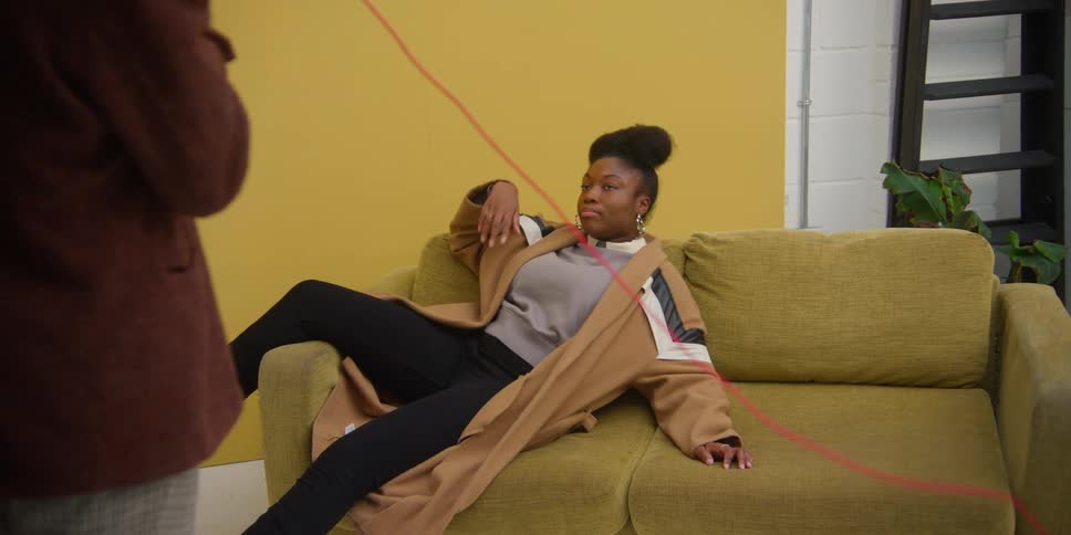 A young woman is photographed on a sofa during a fashion photo shoot