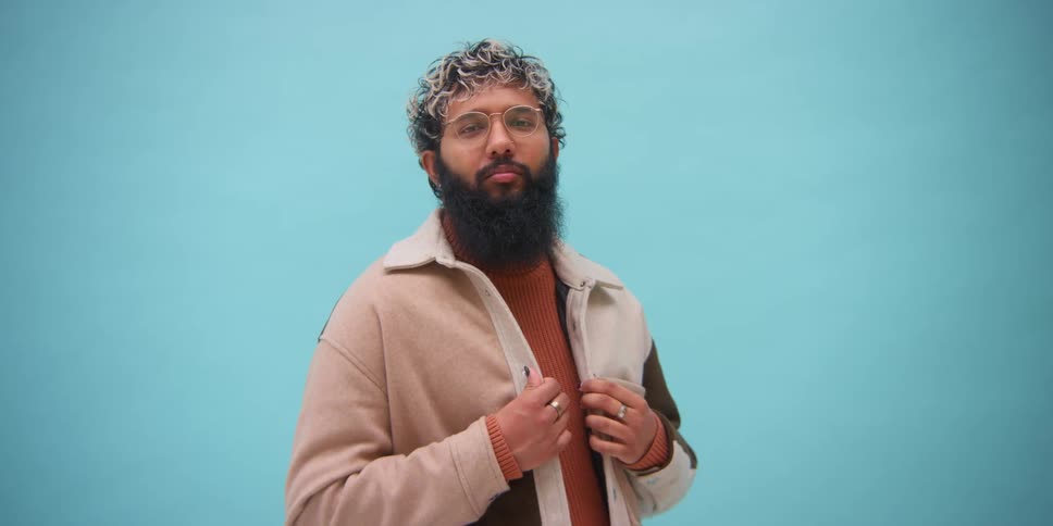 A man in a fashion photo shoot against a blue wall