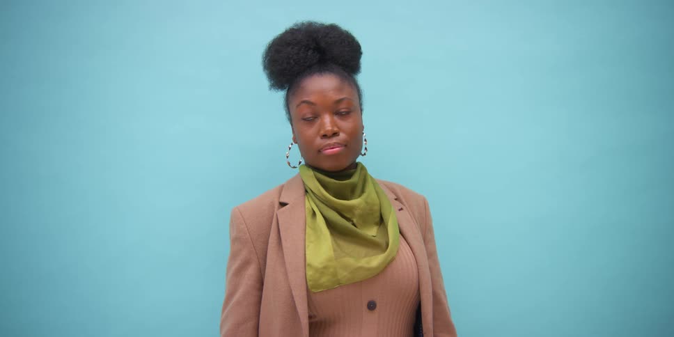Portrait of young black woman looking into camera in front of blue background