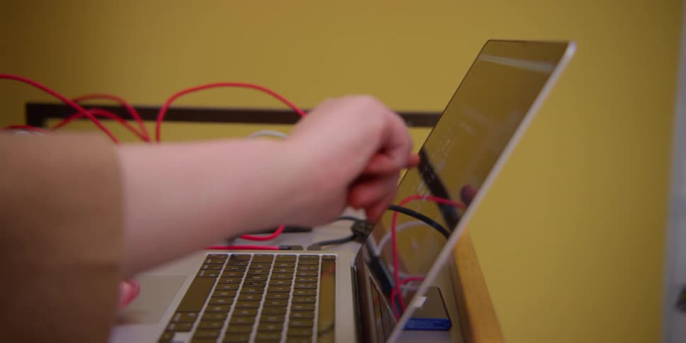A black man works with two other people to get a laptop working